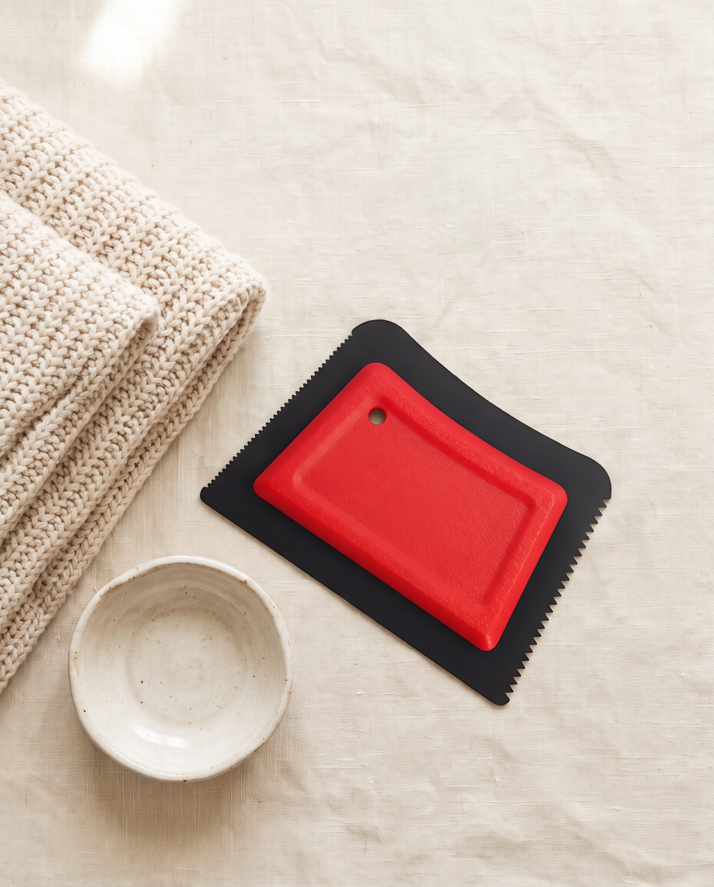 The PawNest pet hair remover beside a folded cream knit blanket